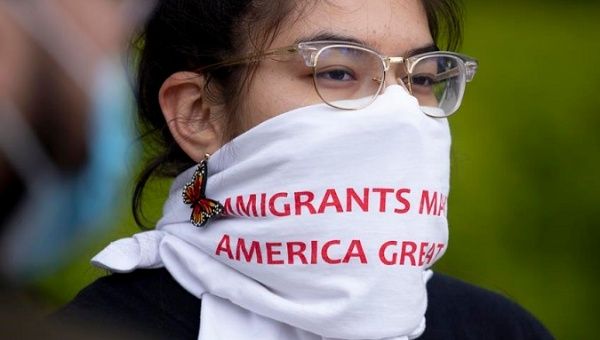 Woman wears a face covering that reads 'Immigrants Make America Great', Washington DC, U.S., April 27, 2020.