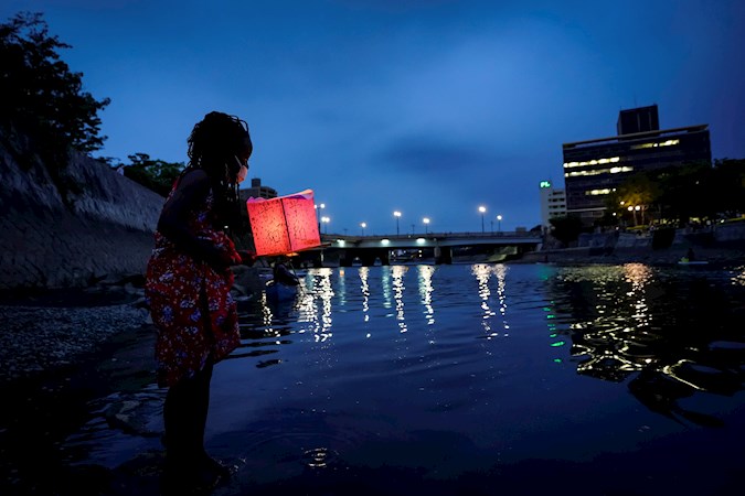 Kenyan girl places a lantern on the water of Motoyasu River near the Peace Memorial Park in Hiroshima, Japan, August 6 2020.
