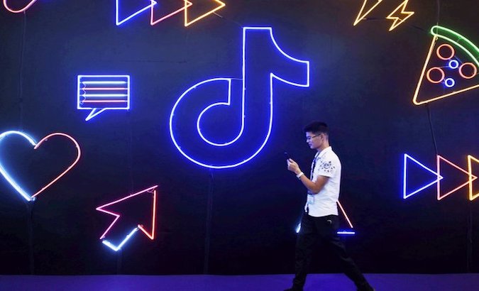 A young man walks in front of a TikTok ad, Bejing, China.