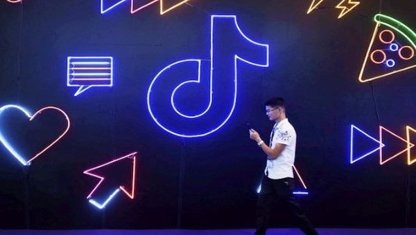 A young man walks in front of a TikTok ad, Bejing, China.