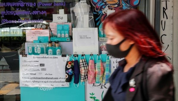 A woman wearing a protective masks walks past a stall selling protective masks, hand sanitizer and face shields in Bangkok, Thailand. August 18 2020. 