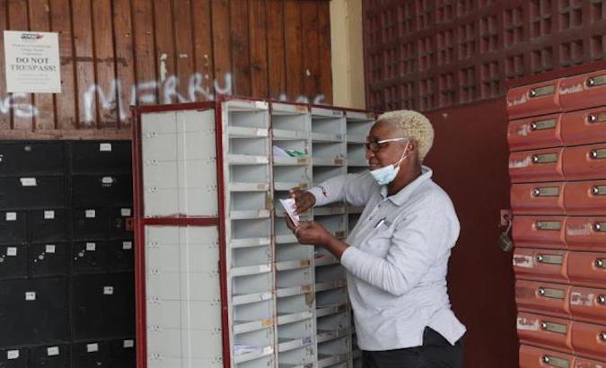 A postal worker delivers letters to mailboxes at the Carenage office in Trinidad and Tobago, May 8, 2020.
