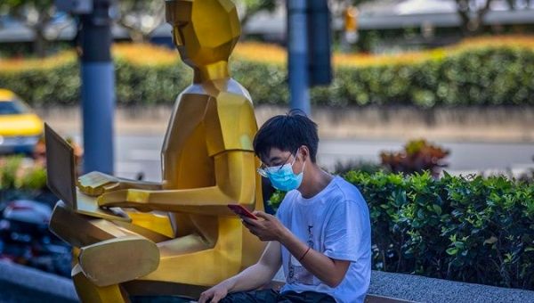 A man uses his phone next to a sculpture in Shanghai, China, August 3, 2020.