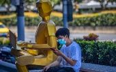 A man uses his phone next to a sculpture in Shanghai, China, August 3, 2020.