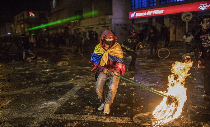 A young man holds a torch during protests in Bogota, Colombia, Sept.10, 2020.