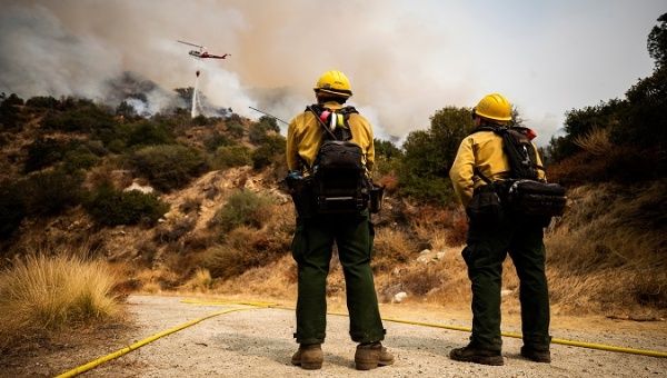 Two firefighters watch a helicopter drop water on the Bobcat fire, burning in the Angeles National Forest, near Arcadia, California, the U.S. September 14, 2020.