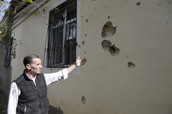 A man shows bullet and shell holes on a house damaged during the new round of Nagorno-Karabakh conflict between Azerbaijan and Armenia in Fuzuli district of Azerbaijan, Sept. 30, 2020.