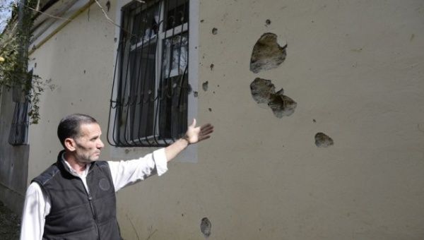 A man shows bullet and shell holes on a house damaged during the new round of Nagorno-Karabakh conflict between Azerbaijan and Armenia in Fuzuli district of Azerbaijan, Sept. 30, 2020.