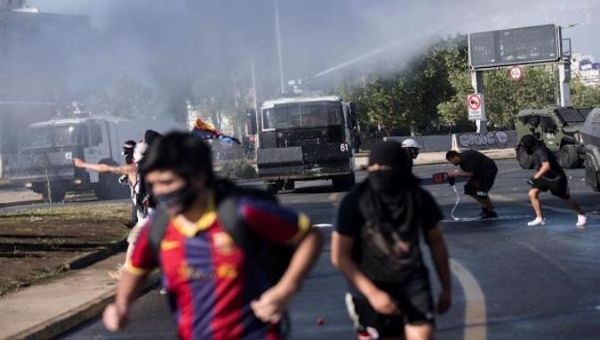 A group of protesters flee from cars throwing water during a protest at Plaza Italia in Santiago, Chile, Oct. 09, 2020.