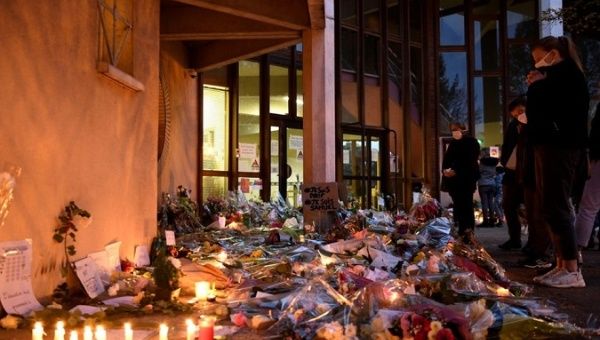 People leave flowers and candles at the school where teacher Samuel Paty was killed in Paris, France, Oct.17, 2020