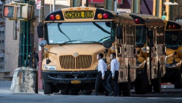 Children walk past school buses in the Borough Park neighborhood in the Brooklyn borough of New York, the United States, Oct. 4, 2020.