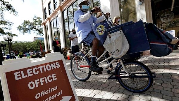 A US mail carrier peddles past the St. Petersburg Supervisors Election Office. 34 States have early voting for the 2020 US Presidential Election and over 62 million people have already voted. St. Petersburg, Florida, USA. October 27, 2020.