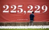 A man pauses in front of a sign showing a number representing a the US COVID-19 death toll, at a memorial for people who died with COVID-19. Washington, DC, USA. October 27, 2020.