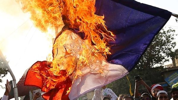 People burn a French flag during a protest against comments over Prophet Muhammad caricatures, as they celebrate Mawlid al-Nabi, birth anniversary of Prophet Muhammad. Karachi, Pakistan. October 30, 2020.