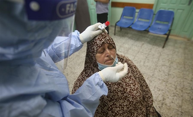 A medical worker collects a swab from a woman for a COVID-19 test, Rafah city, Gaza Strip, Nov. 1, 2020.