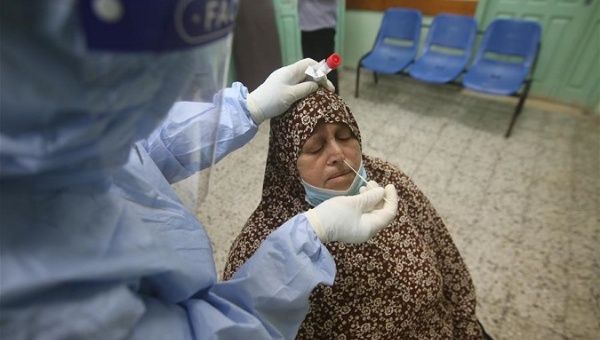 A medical worker collects a swab from a woman for a COVID-19 test, Rafah city, Gaza Strip, Nov. 1, 2020.