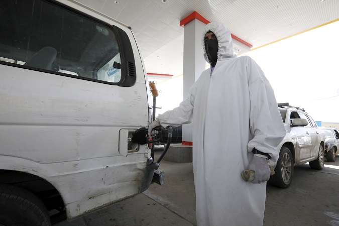 An attendant wearing personal protective equipment pumps fuel into a vehicle at a petrol station amid an acute shortage of fuel supplies in Sana'a, Yemen.