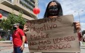 A woman holds up a sign that reads, "We are no military target, No more social leaders murdered," during the National Strike, Bogota, Colombia, Nov.19, 2020.