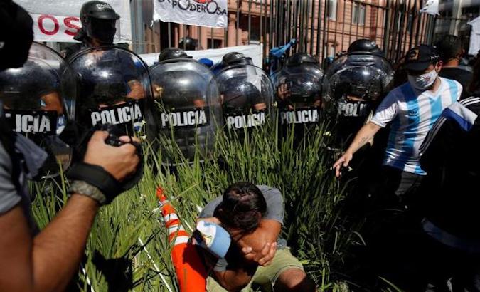 Police agents surround a citizen during clashes in Buenos Aires, Argentina, Nov. 26, 2020.