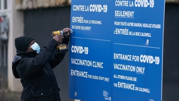 Workers set up signs at the first center to recive Covid-19 vaccine in Montreal, Canada, 14 December 2020.