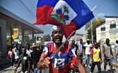 A protester holds the Haitian flag, Port-au-Prince, Haiti, 2019. 