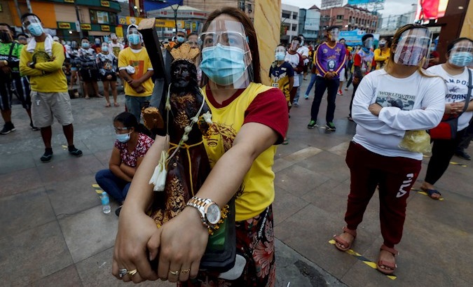 Citizens marking the Black Nazarene feast day participate in a mass from outside the Quiapo church, Manila, Philippines, Jan. 9, 2021.