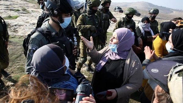 Palestinian women argue with Israeli soldiers during a protest in the west bank village of Al-Rakeez south of Hebron, Jan. 3, 2021.