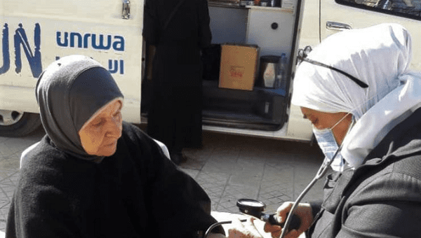 Woman receives medical assistance provided by UNRWA, 2020.