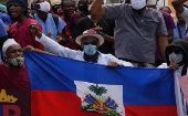 People hold an Haitian flag during a protest in Port-au-Prince, Dec. 2020.