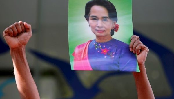 Man raises a photograph of Aung San Suu Kyi during a protest at the Myanmar embassy in Bangkok, Thailand, Feb. 1, 2021.