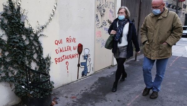 People walk past a graffiti written 