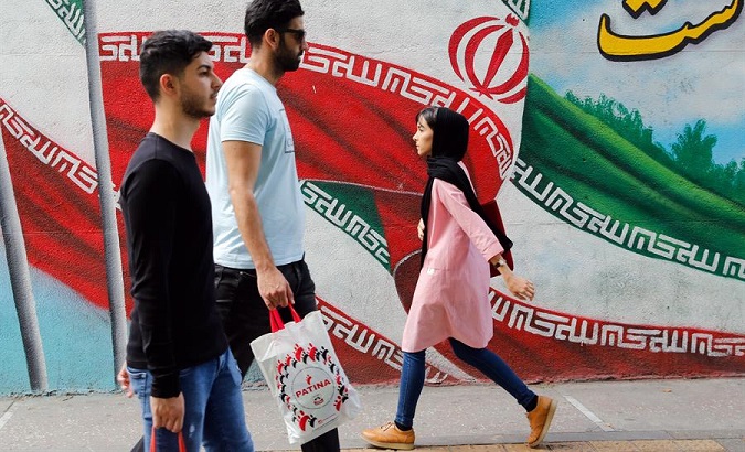 Iranians walk past a mural decorated with their country's flag, Tehran, Iran, May 5, 2019.