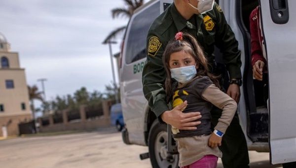 Migrant girl is led into a car by a U.S. official.