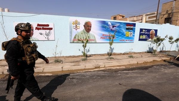 An Iraqi policeman walks next to posters of Pope Francis outside the St. Joseph Chaldean Catholic Church in Baghdad's Karada district, Iraq on 03 March 2021.  