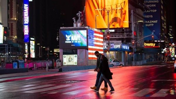 Pedestrians walk across the street on Times Square, New York, U.S., March 24, 2021. 