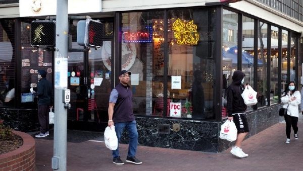 People holding take-away food walk past a restaurant in San Mateo, California, U.S., March 26, 2021.