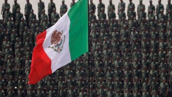 Dozens of military personnel stand in front of a Mexican flag, Mexico City, Mexico.