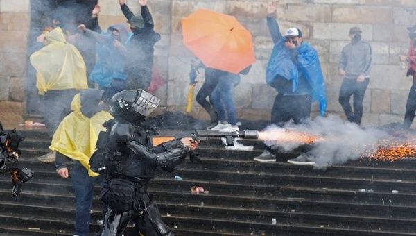 A policeman shoots at citizens during International Workers' Day, Bogota, Colombia, May. 1, 2021.
