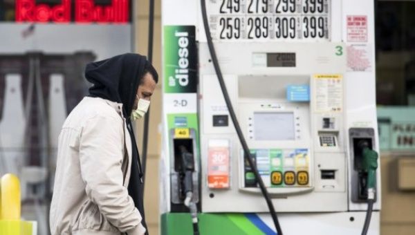 A man wearing a face mask passes by a gas pump at a gas station in the Brooklyn borough of New York, the United States, on April 20, 2020.