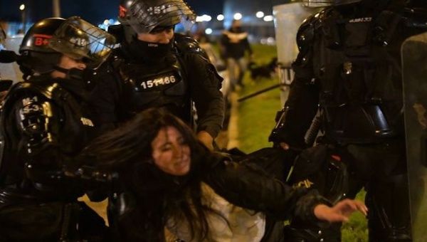A woman is detained by several police officers in Cali, Colombia, May 2021.