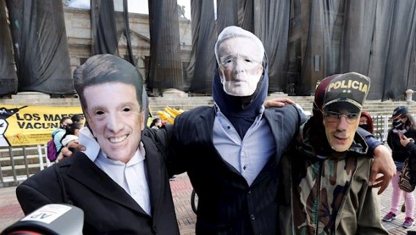 Protesters wear masks alluding to the Colombian Defense Minister Diego Molano (i), former president Álvaro Uribe (c), and General Jorge Luis Vargas, director of the National Police, during a sit-in in support of the motion of censure against Molano, in the Plaza de Bolívar, in Bogotá