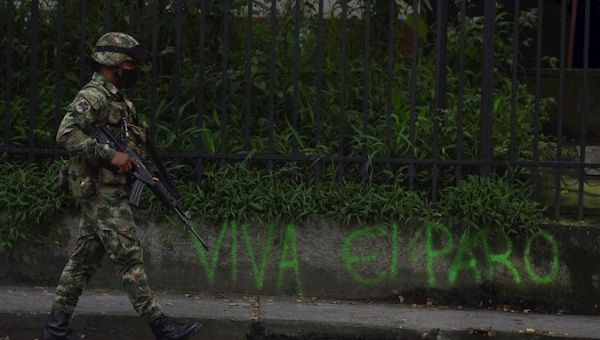 A Colombian soldier passes by a sign calling for strike support