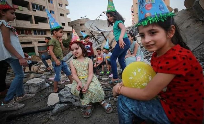A Palestinian family celebrates their son’s birthday on the rubble of their house, Gaza, May 27, 2021.