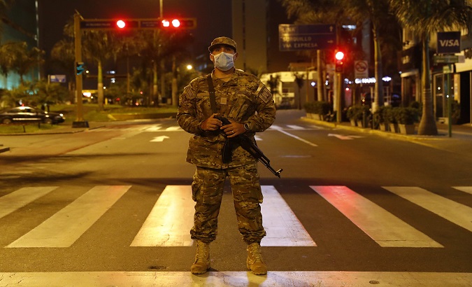 A military man watches over the curfew in Lima, Peru, March. 18, 2020.