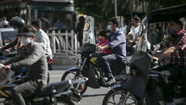 People wearing face masks ride motorcycles on a street in Tehran, Iran, on May 31, 2021.