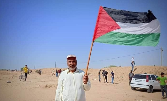 Citizen waves the Palestinian flag near the border with Israel, Aug. 2021.
