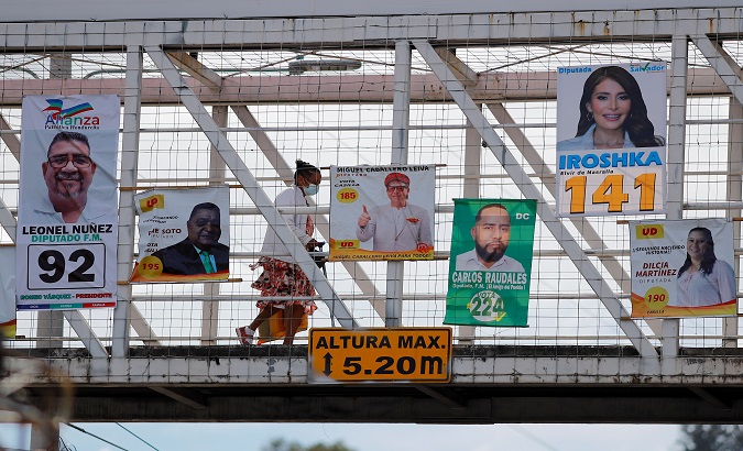 A woman walks across a bridge where political posters have been installed, Tegucigalpa, Honduras, Nov. 23, 2021.