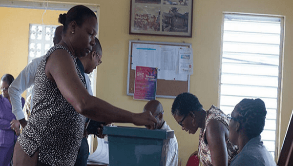A woman enters her ballot at a voting booth, Barbados. 