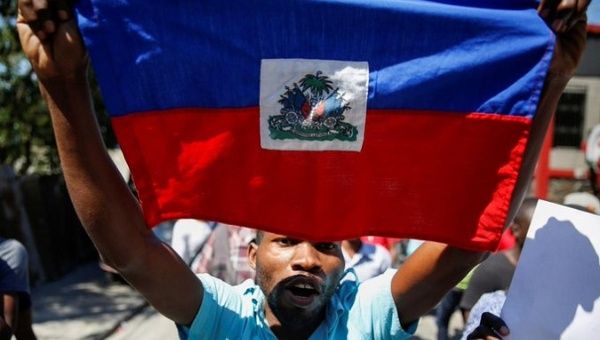 Citizen holds the flag of Haiti during protests.