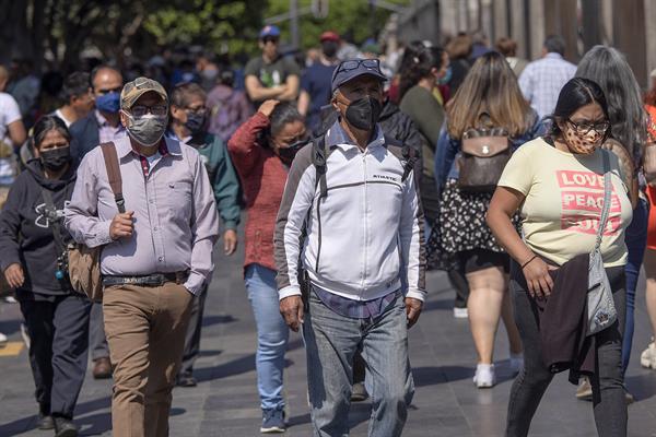 People with masks walk today through the streets of the historic center of Mexico City